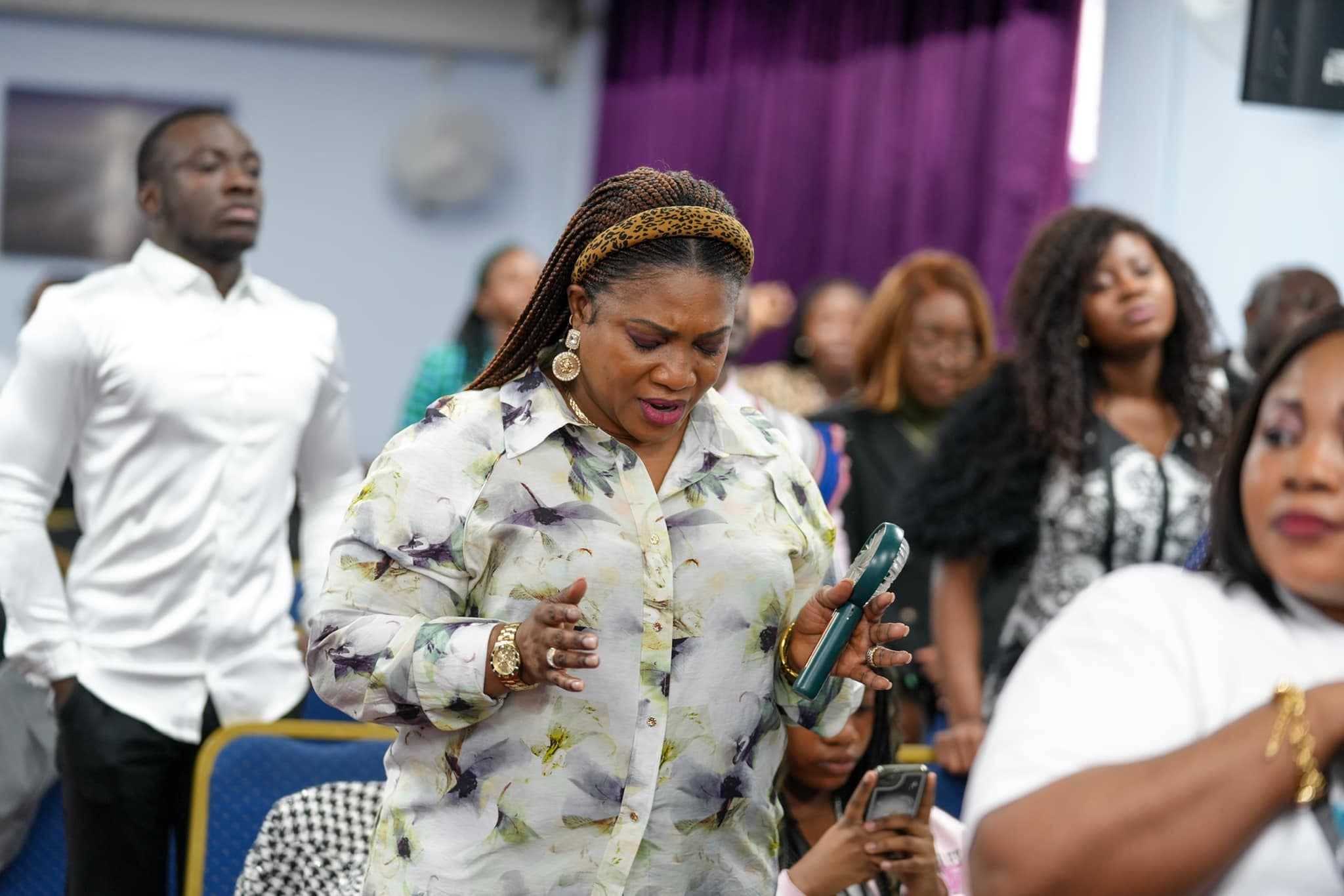 A woman deep in worship among the congregation at ICC Luton
